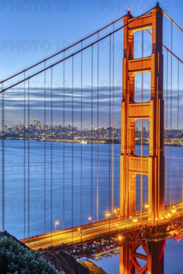 Detail of the famous Golden Gate Bridge at dawn with the San Francisco skyline in the background
