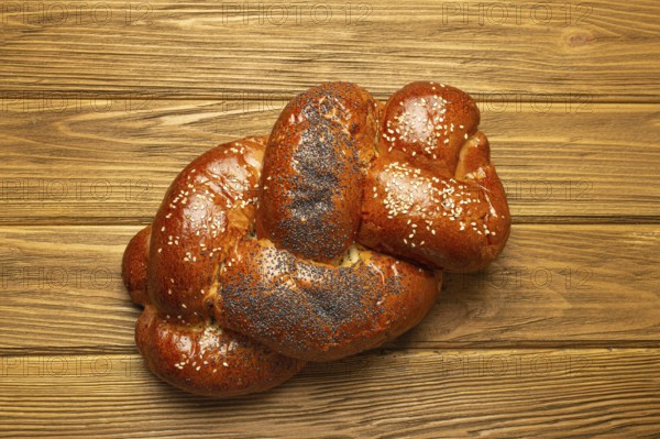 Freshly baked Challah bread covered with poppy and sesame seeds, top view on rustic wooden background, traditional festive Jewish cuisine, food photography, food photography