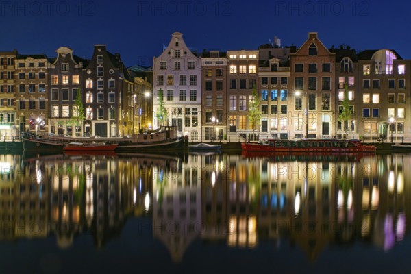 Reflection of the buildings along the canal at night in Amsterdam, Netherlands