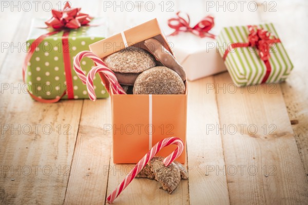 Orange colored gift box full of sweets, gingerbread and candies, on a wooden table