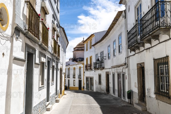 Evora, Portugal, June 30, 2022: Street in the old town with typical whitewashed houses with balconies. Alentejo, Portugal, Europe