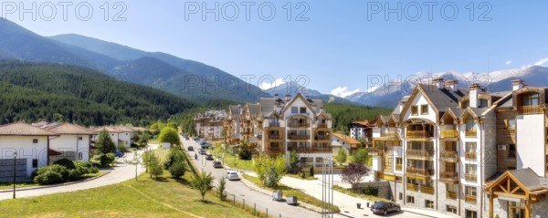 Bansko, Bulgaria, August 17, 2023: Summer street view with houses and Pirin peaks banner panorama in the upper part of the town, Europe