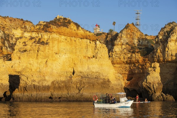 Stand-up paddler and fishing boat at Ponta de Piedade, Lagos, Algarve, Portugal, Europe