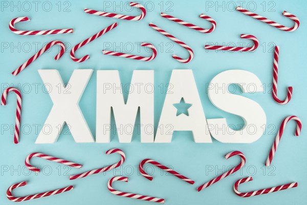 Zuckerstangen und hölzerne XMAS-Buchstaben auf blauem, hellem Hintergrund