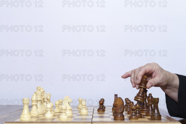 Close-up of a woman's hands playing chess with a white background and copy space