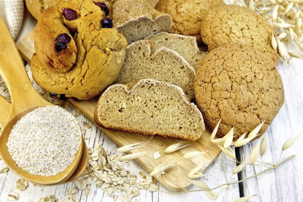 Bread, rolls and biscuits oat, bran in a spoonful, oat stalks on a background of wooden boards