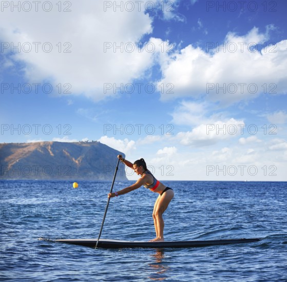 SUP Stand up Surf girl with paddle in a blue ocean sea