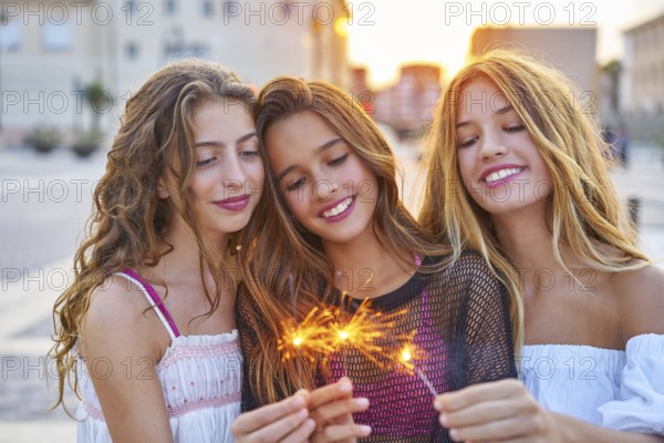 Best friends teen girls with sparklers at sunset in the city