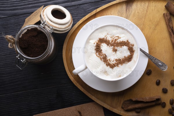 Porcelain cup of coffee with ice cream and cinnamon heart served at black wooden table. life style concept