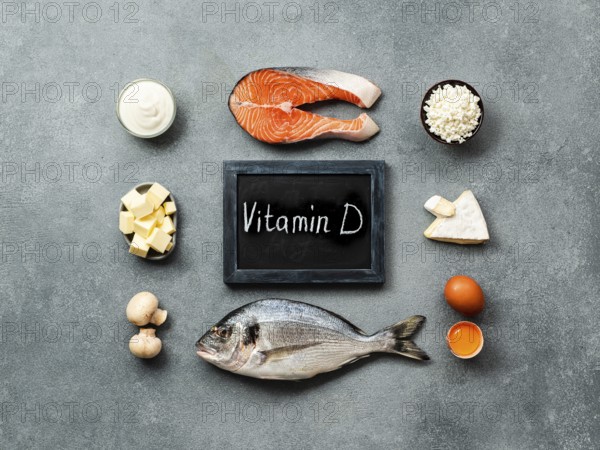 Vaitamin D sources concept. Fish, salmon, dairy products, eggs, mushrooms and chalkboard with Vitamin D words on gray stone background. Top view or flat lay