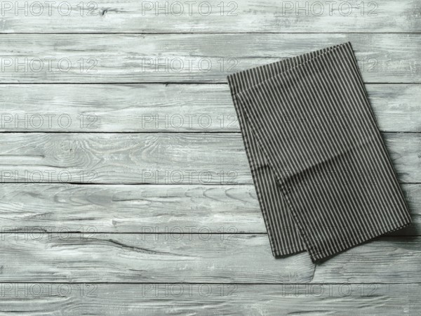 Gray wooden table with balck and white dark linen kitchen towel or textile napkin flat lay. Dark tablecloth on old gray wood tabletop. Copy space for text. Can use as mock up for design