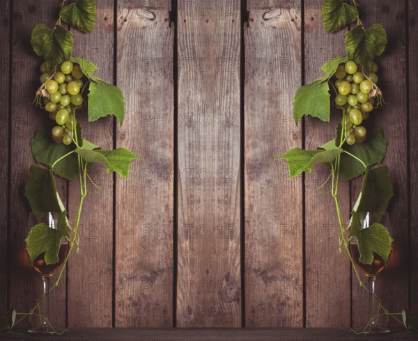 Grapes with leaves and glass of wine on the wood background