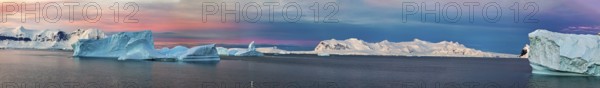 Panoramic view of icebergs in the sea under a coloured sky, icebergs in the Southern Ocean in Antarctica