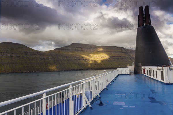 Blue sun deck of a ferry with the coast of the Faroe Islands in the background