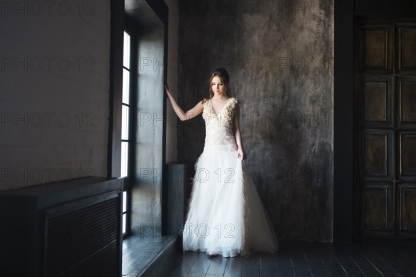 Portrait of beautiful young woman on dark background near the window