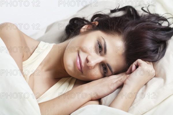 Pretty young brunette woman lying in bed, Belgium, Europe