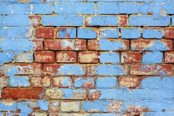 Fragment of old brick wall with shelled blue paint layers