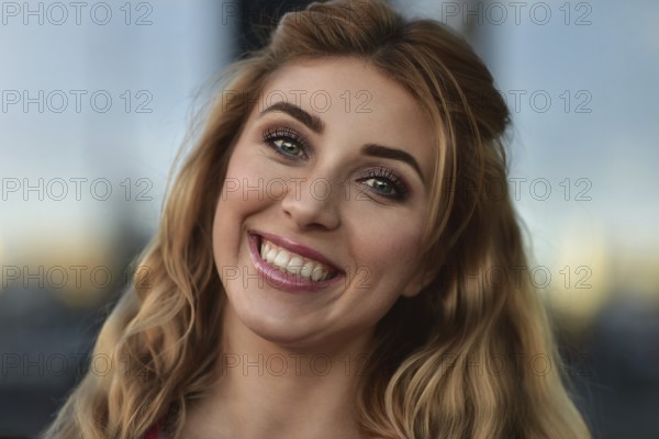 Closeup portrait of beautiful pensive blonde white Caucasian girl woman, weared in red jacket outside in city street, lifestyle portrait concept