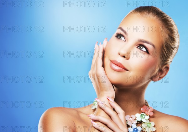 Beautiful woman with dark makeup and pink lipstick posing on blue background wearing flower spring and summer jewellry necklace, Toronto, Canada, North America