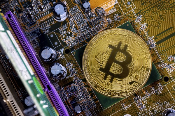 Virtual cryptocurrency money Bitcoin golden coin on a computer printed circuit board PCB. The future of money. Computational equipment. Shot directly from above