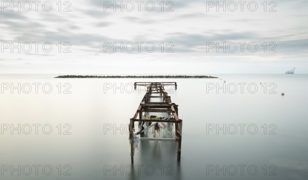 Seascape with old deserted industrial jetty at sunset. Abandoned damaged pier in the ocean. Long exposure Cyprus