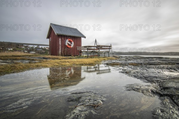 Beautiful coastal photo at sunset. Landscape shot of a steep coast in a nature reserve. Typical Swedish buildings can be found in the picture Red House. Grebbestad, Sweden, Scandinavia, Europe