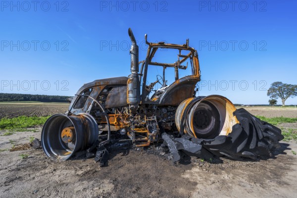 Fully destroyed burnt down tractor on a field
