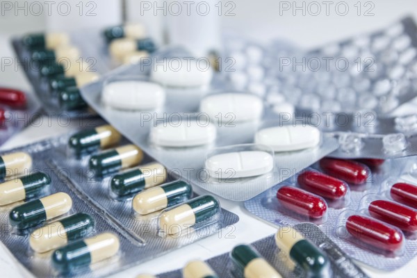 Assorted blister packs featuring a variety of pills and capsules in white and red