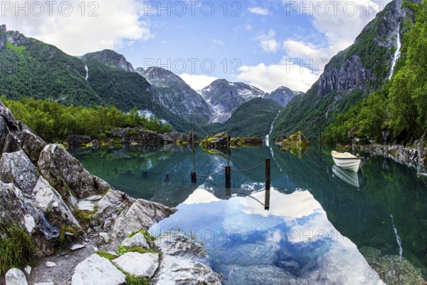 The boat is reflected in the clear water of the lake. Gorgeous Norway. Emerald green of summer grass. The mountain lake Bondhuswatnet. The picture was taken with a fisheye lens