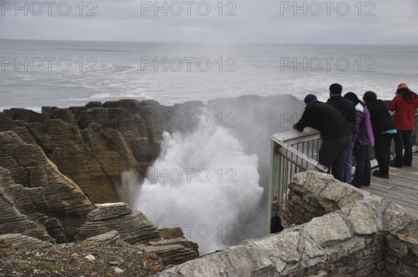 PUNAKAIKI, NEW ZEALAND, MAY 5, 2010: Tourists enjoy the main blowhole in action at the Pancake Rocks, Punakaiki, West Coast, South Island, New Zealand, Oceania