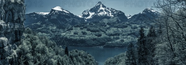 Great panorama over the lake Walensee and its beautiful surroundings, the snowy mountain peaks and huge cliffs, with dark blue colors added. Picture taken near the village Quinten, Switzerland, Europe