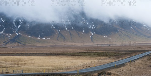 Rural empty straight road with mountains covered in fog at in Reykjanes peninsula in Iceland
