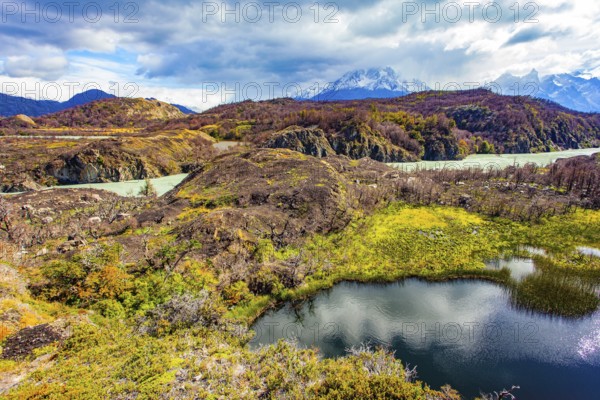 The picturesque River Gray is fed by the glacial melt waters of Lake Gray. Magnificent park Torres del Paine. Chile. The sky and clouds are reflected in the smooth water