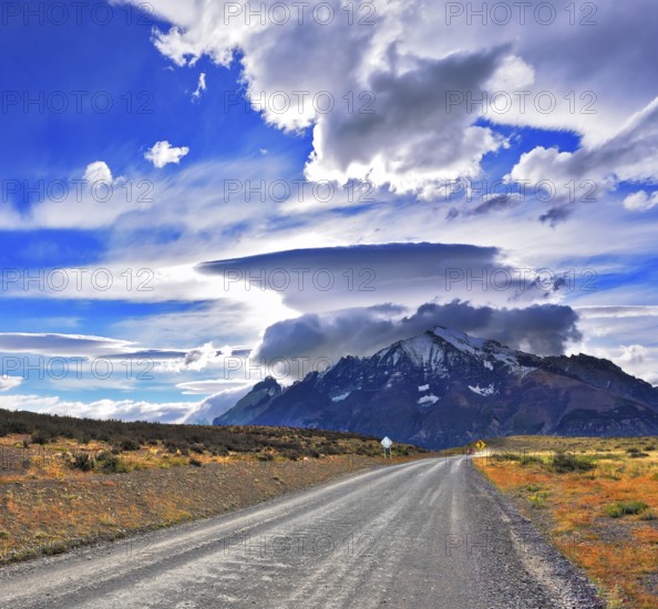 Stunning sunset in the Chilean Patagonia. Incredible clouds over the mountain glaciers. The dirt road leads to the mountain range