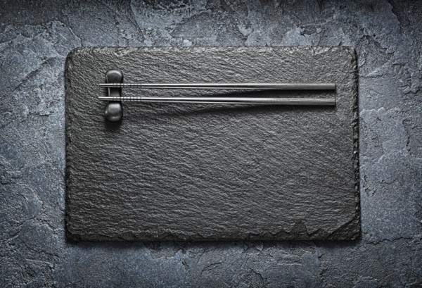 Black Choppingsticks On Rest And Stone Slate Platter