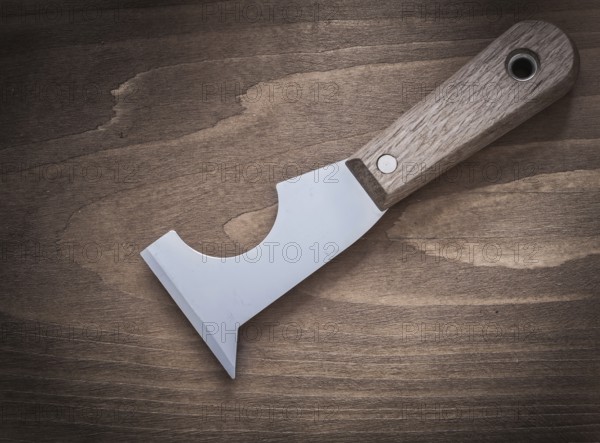 Stainless putty spattle on vintage wooden board construction concept