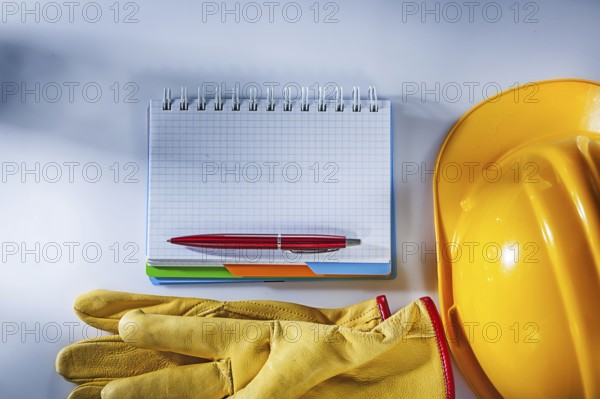 Protective gloves building helmet notepad pen on white background