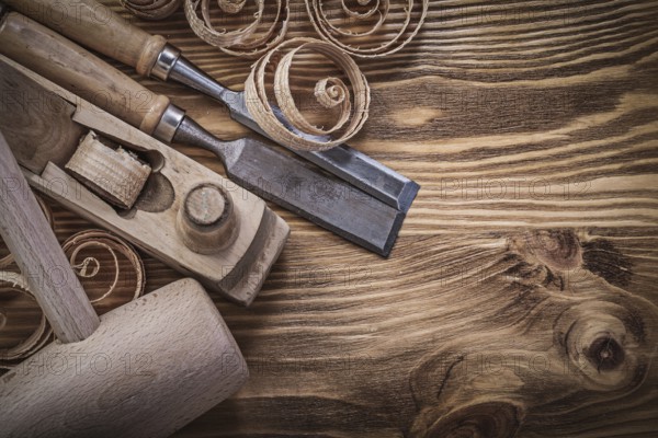Flat chisels shaving plane curled shavings lump hammer on wooden board construction concept