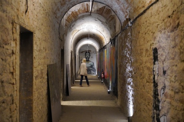 MAUSA VAUBAN, Museum of Urban Art and Street Art, Neuf-Brisach Fortress, France, Europe, Illuminated brick walkway with artworks on the walls and a person walking through it, Europe