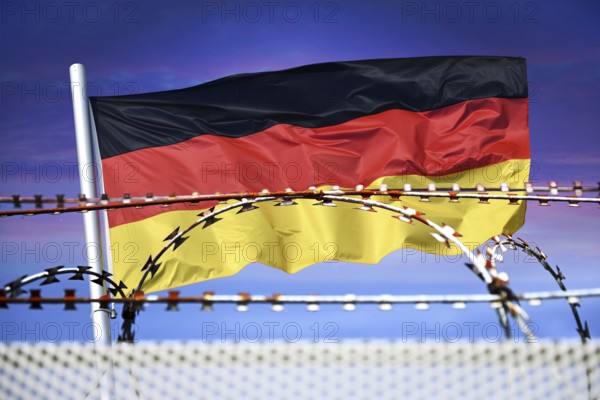 German flag in front of barbed wire, symbolic photo for border controls and rejection at the German national borders, photomontage