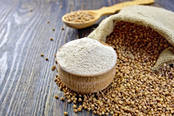 Buckwheat flour in a wooden bowl, buckwheat in a bag on a wooden boards background