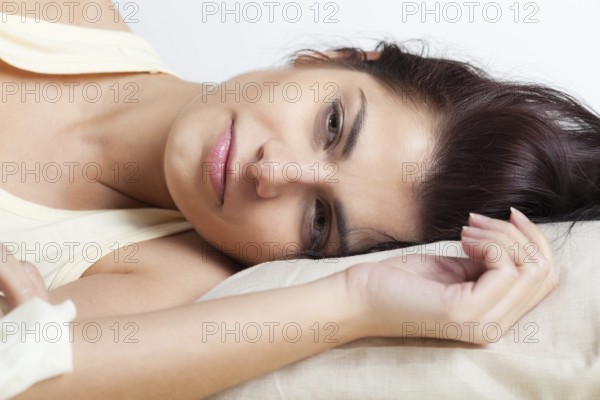 Pretty young brunette woman lying in bed, Belgium, Europe