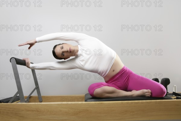 Gym woman pilates instructor stretching in reformer bed