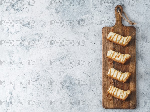 Caramelized cheesecake slices on wooden cuttingboard. Cheesecake on gray cement background with copy space for text. Top view or flat lay