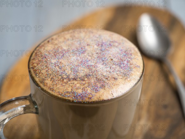 Trendy Coffee with edible glitter. Cup of sparkly coffee or diamond cappuccino on gray table. Copy space for text