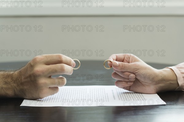 Great concept of divorce, end of relationship, hand of man and woman handing over alliances, divorce agreement