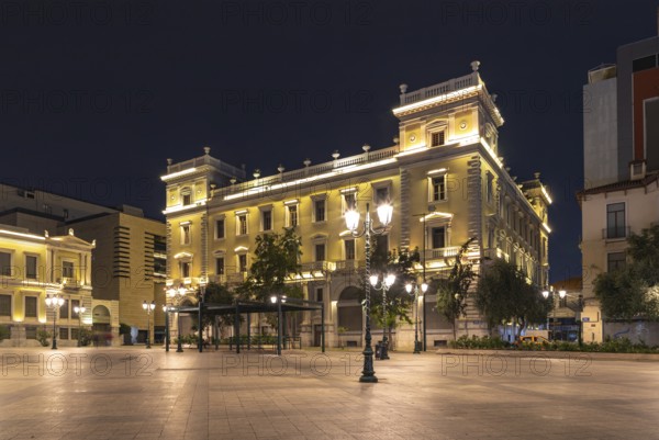 A picture of a yellow building on the Kotzia Square, at night