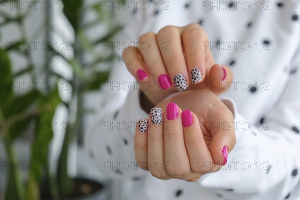 Manicured female hands with stylish pink nails and design. Trendy modern design manicure. Gel nails. Skin care. Beauty treatment. Nail care. Wellness. Trendy colors