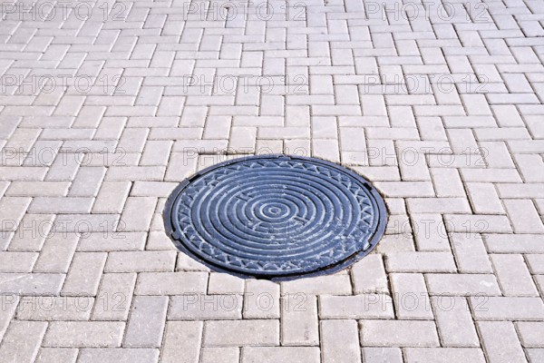 The road of brown tiles with a round metal hatch