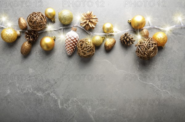 Flat lay view at Christmas decorations of gold and yellow cones glass balls and light garland on stone table. Space for text